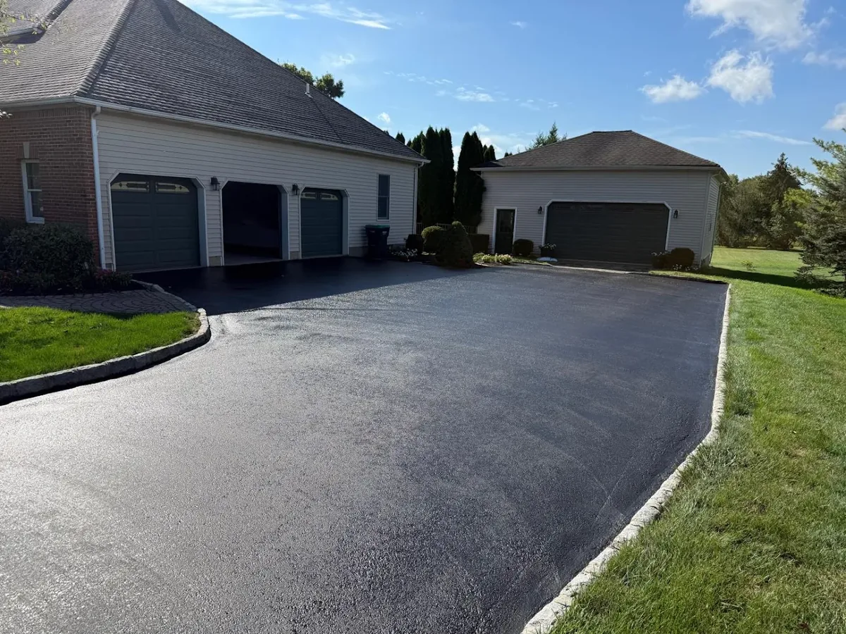Wide black asphalt driveway and parking court in front of a three car garage