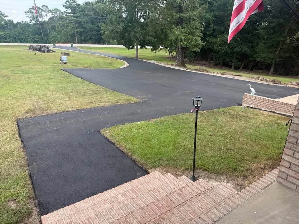 Finished asphalt driveway with a turnaround pad at a home with brick steps