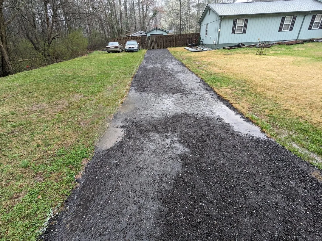 Dark asphalt millings spread and rolled up a sloping driveway