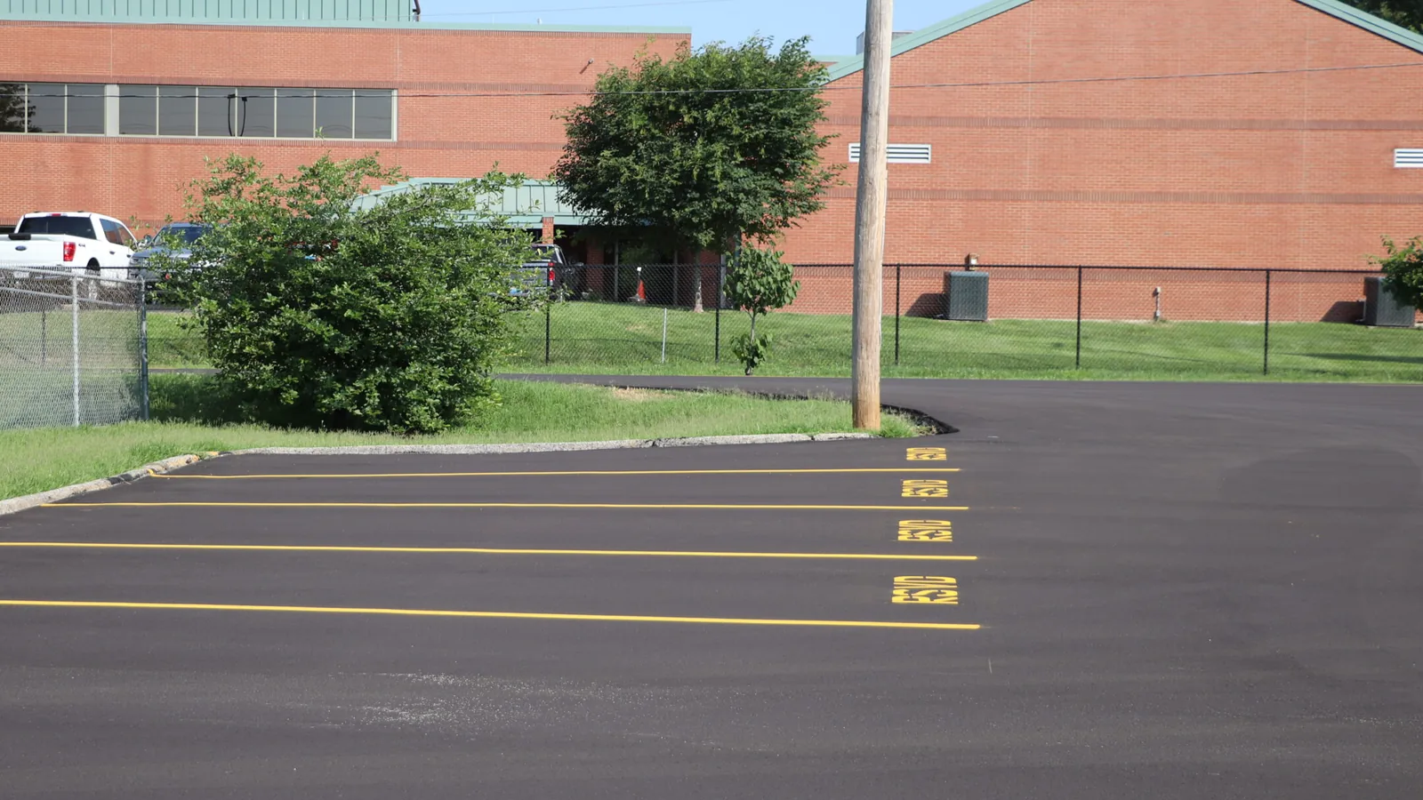 Newly paved lot with fresh yellow stall lines beside a brick building