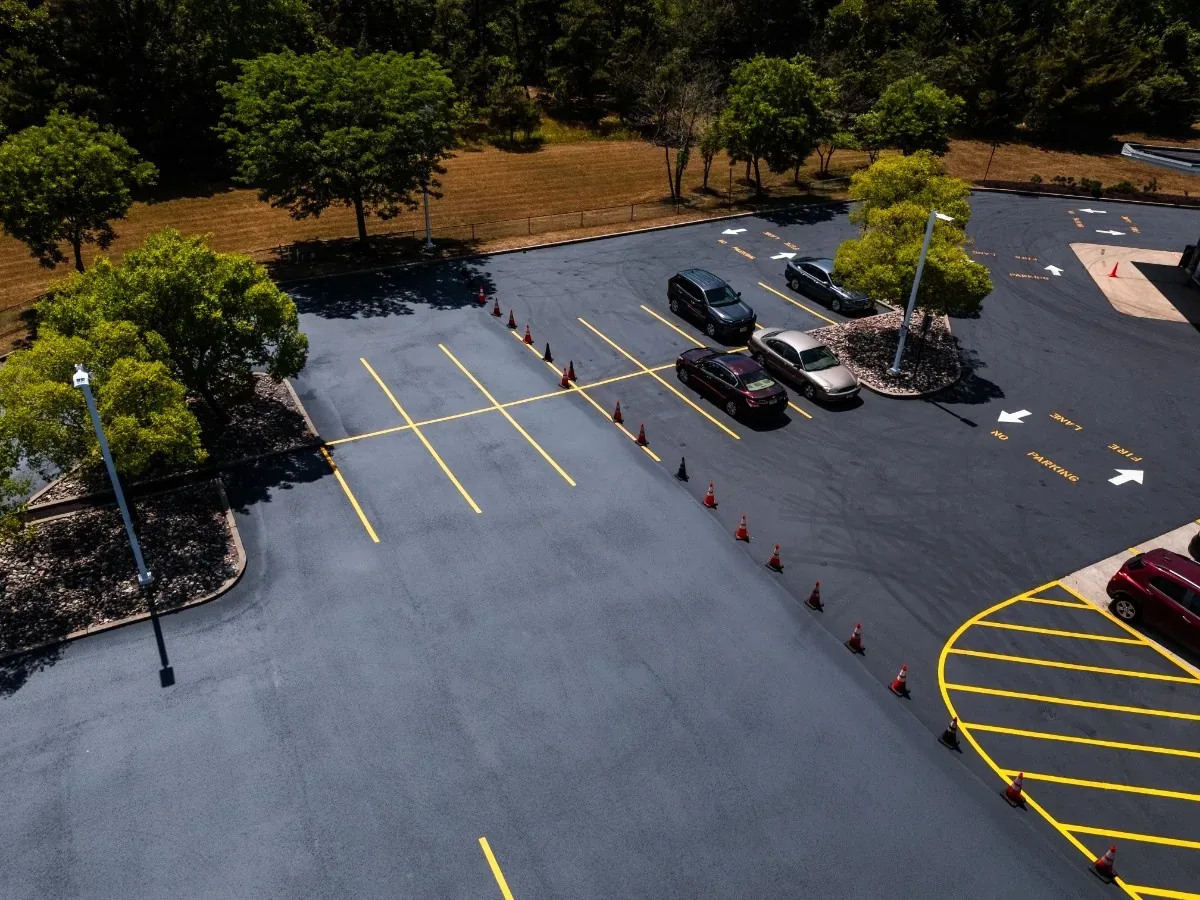 Freshly paved parking lot with new yellow stall lines and cones still in place