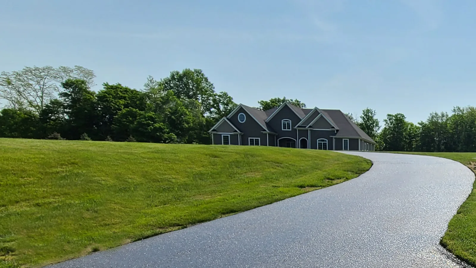 Long sealed asphalt drive running over a rise to a house