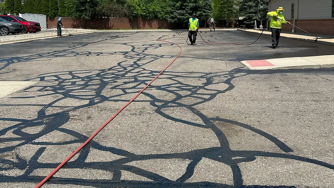 Crew sealing a network of cracks across an asphalt parking lot