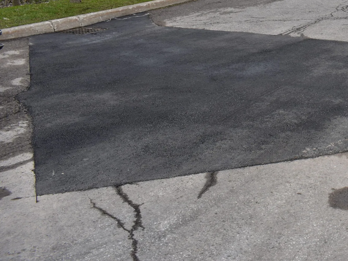 Squared hot mix patch laid into an old cracked asphalt surface