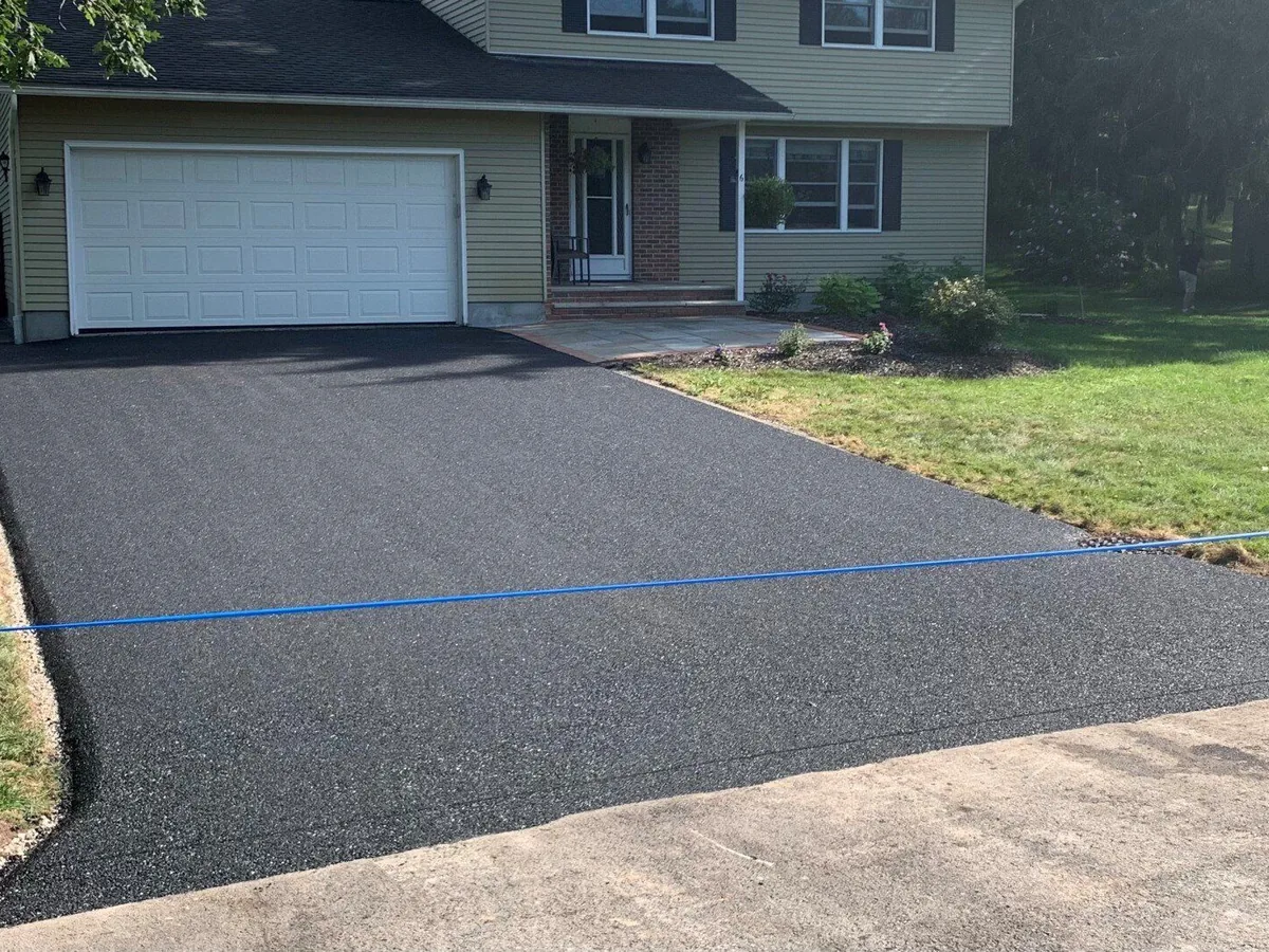 New asphalt overlay tied into the concrete apron at a garage