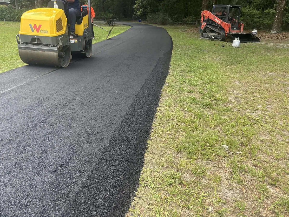 Roller compacting a fresh asphalt overlay on a curving driveway