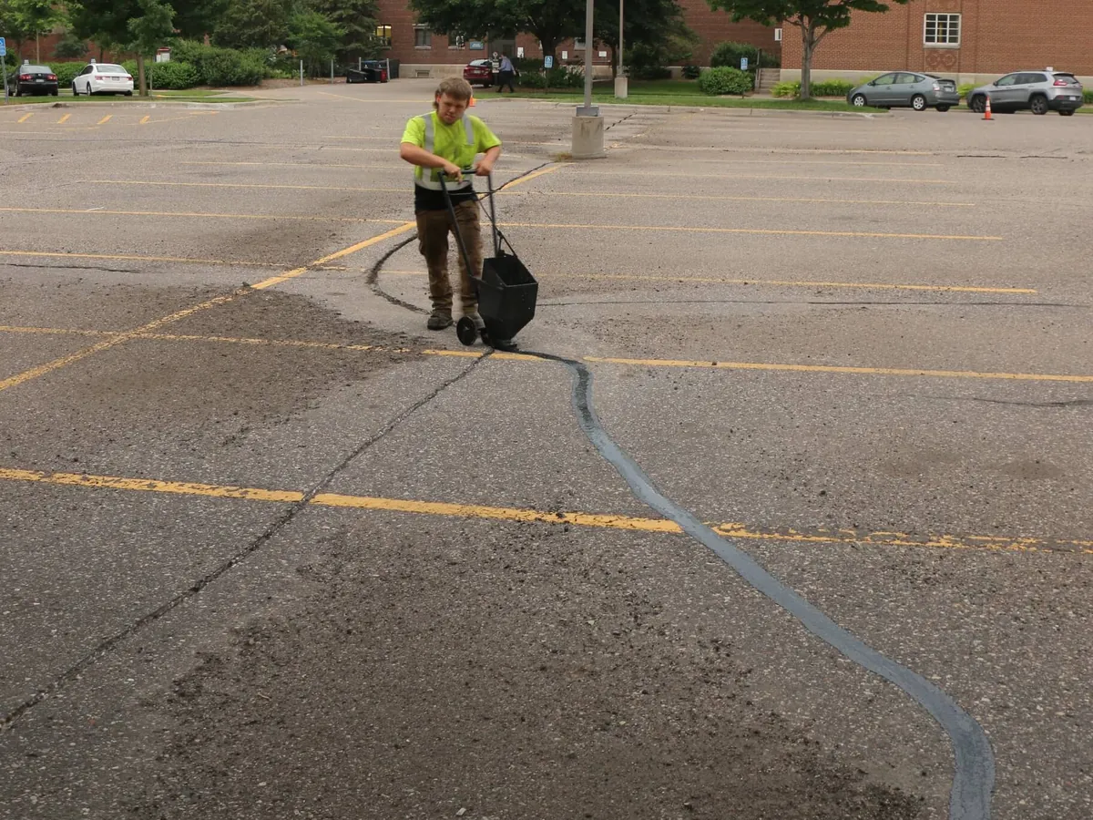 Crack filling a parking lot with a wheeled pour pot