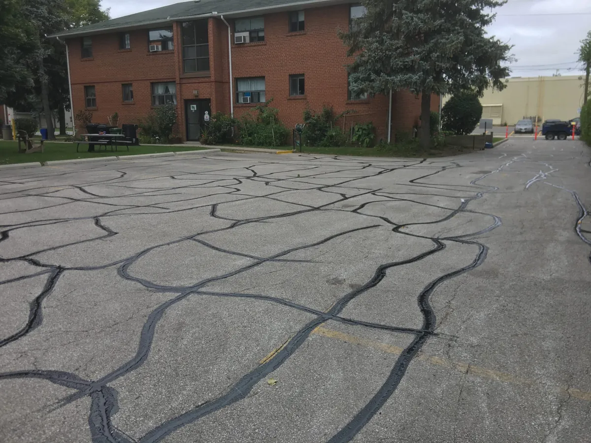 Apartment parking lot with its block cracks sealed in black crack sealant