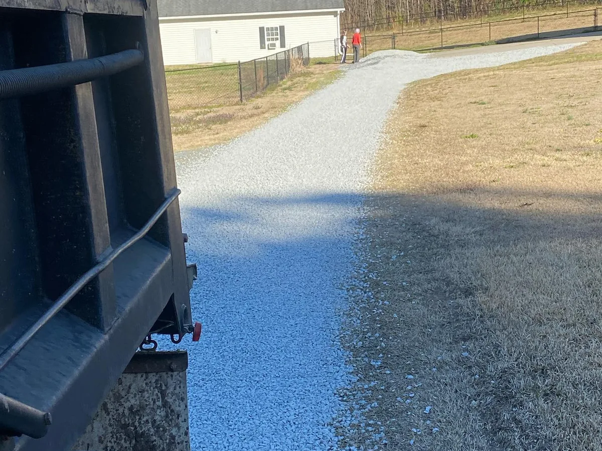 Dump trailer tailgate spreading fresh gravel down a driveway