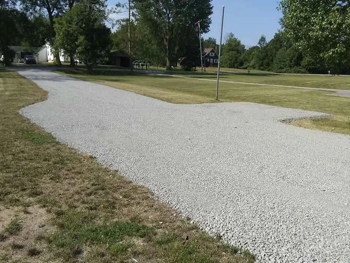 Fresh gravel driveway curving through a green yard