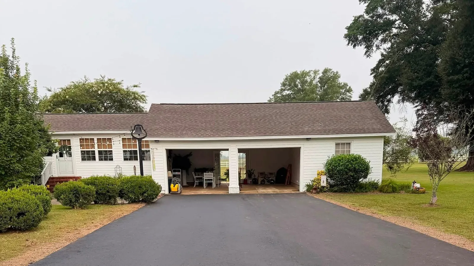 Fresh black asphalt driveway running up to a white house with a carport in south Alabama