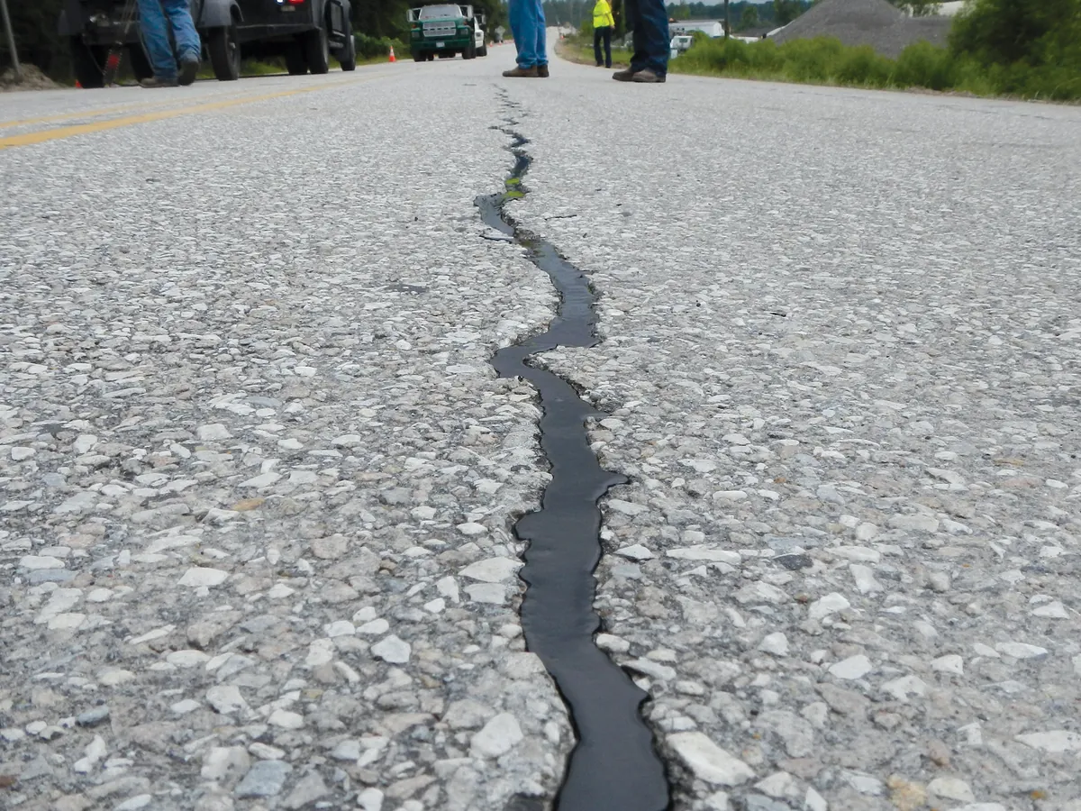 Long crack in an asphalt road filled with black hot-pour sealant