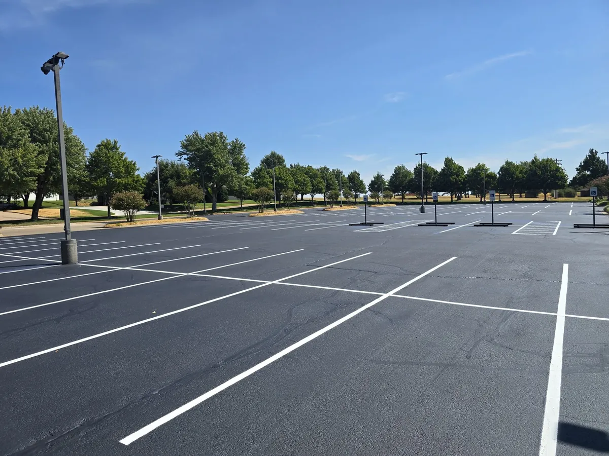 Freshly sealcoated parking lot with new white stall lines and accessible parking signs