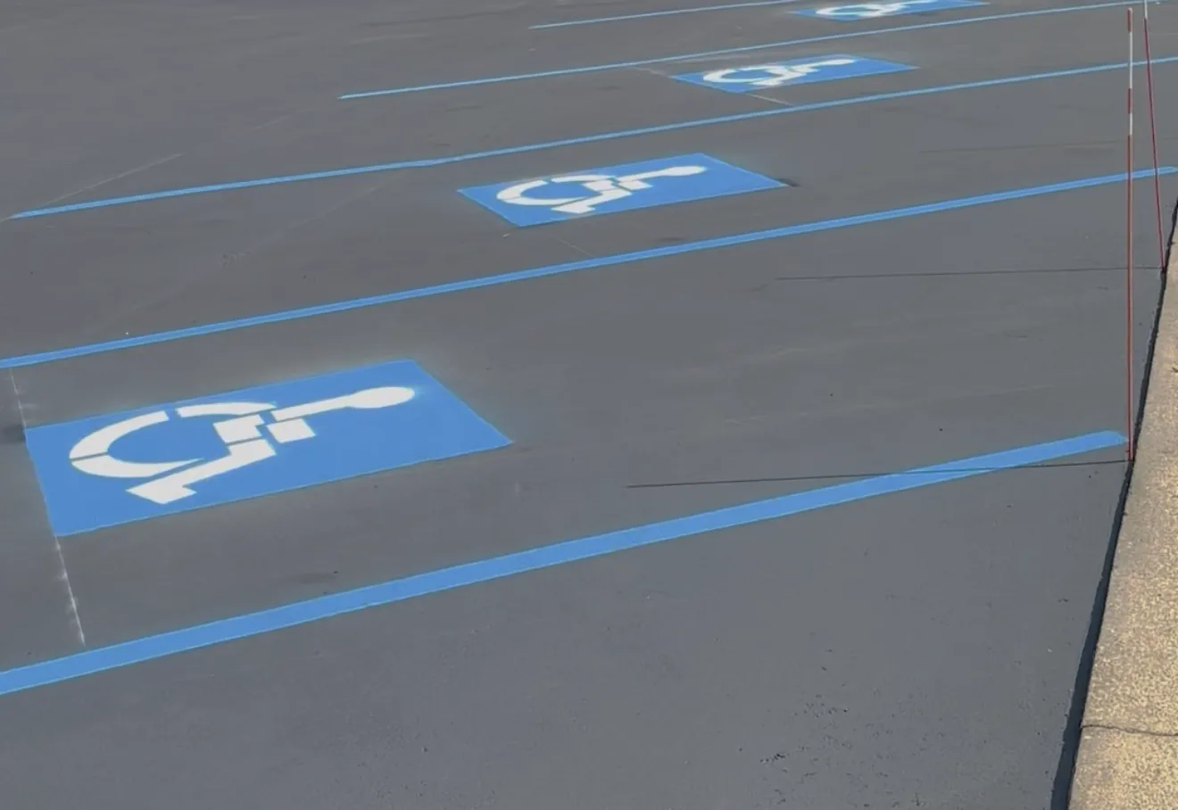 Blue accessible parking spaces and access aisle painted on a freshly striped lot