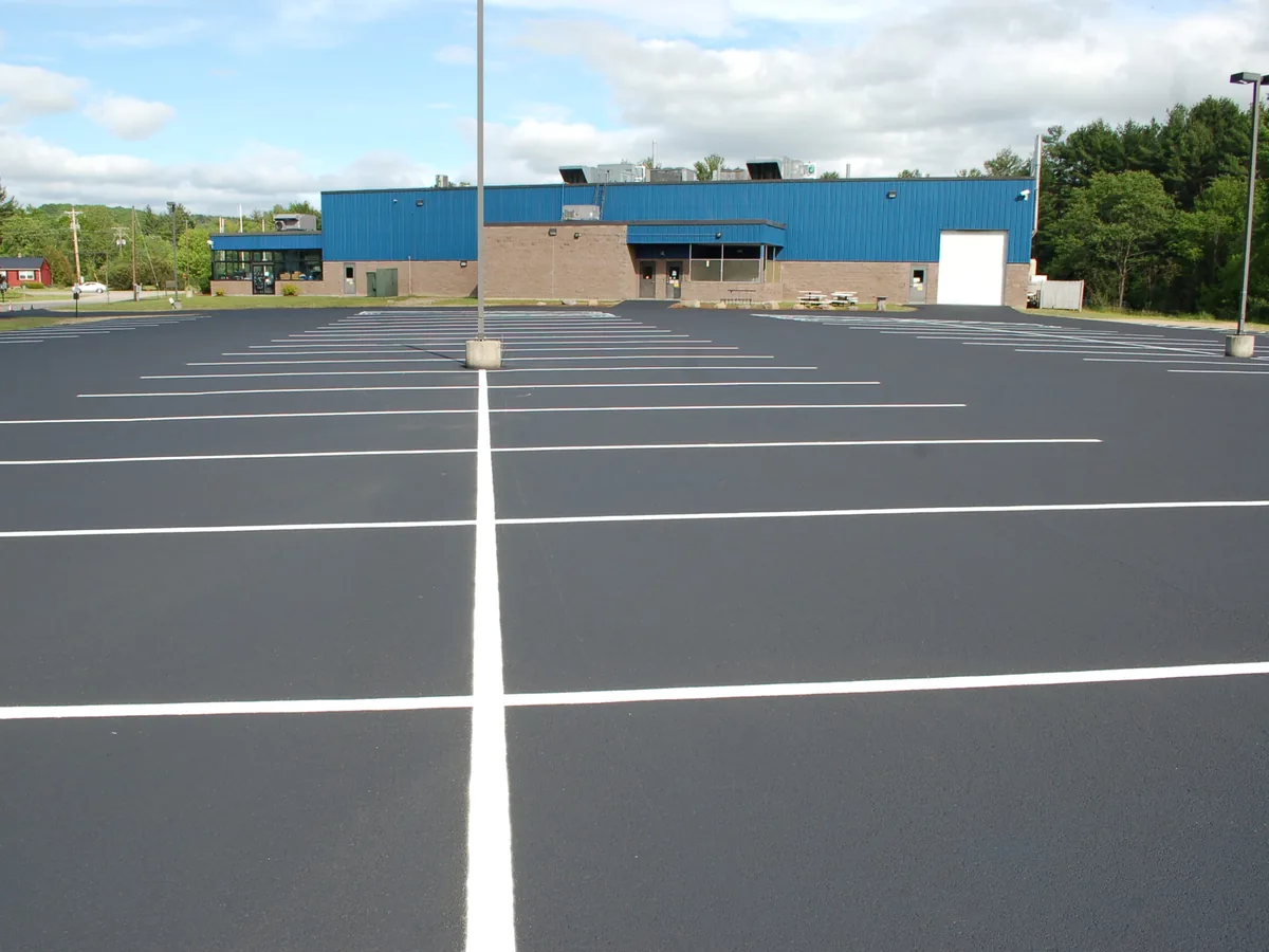 Freshly striped white stalls across a newly sealed commercial parking lot