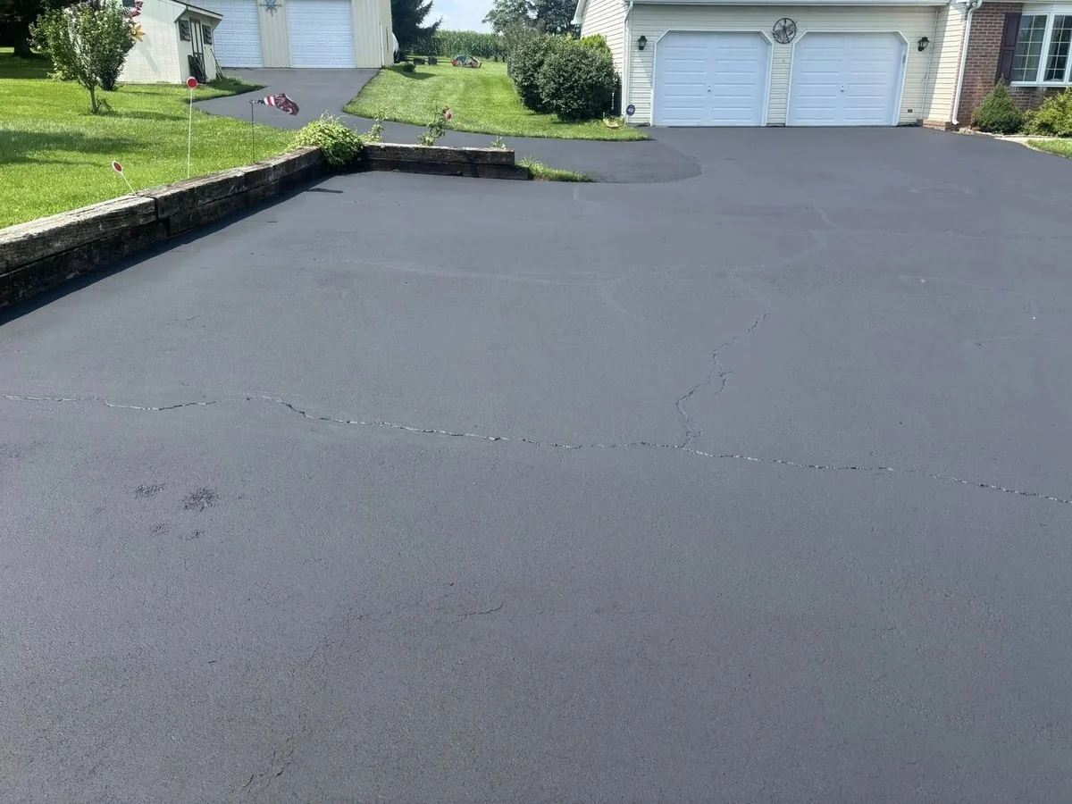 Freshly sealed asphalt parking area and driveway beside a garage